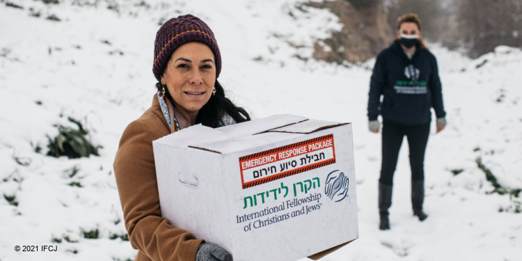 Yael Eckstein holding an IFCJ branded food box in the snow.