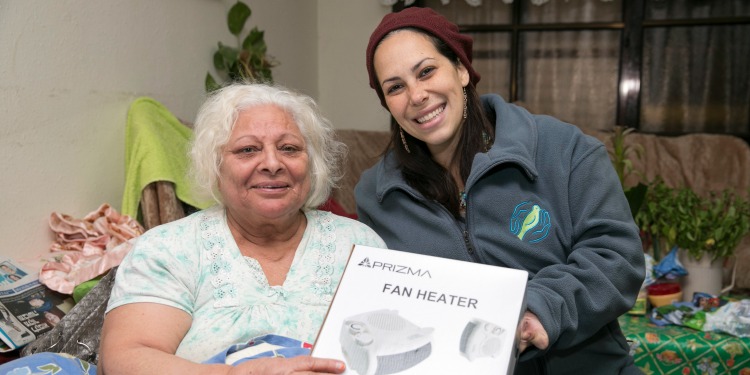 Yael Eckstein with an elderly Jewish woman holding a fan heater that was given to her by the Fellowship.