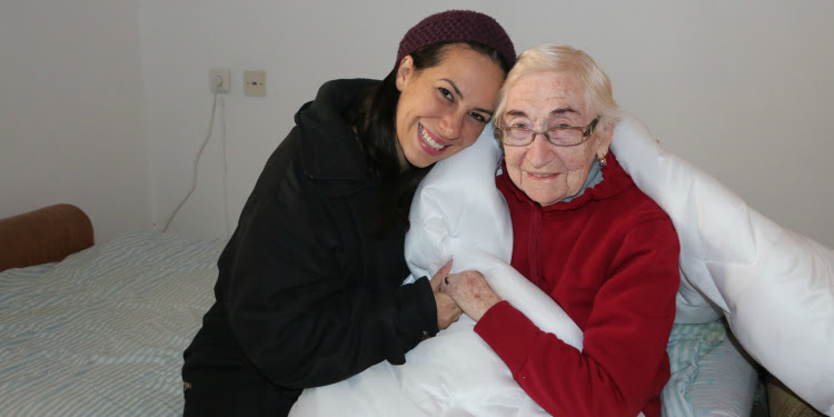 Yael Eckstein sitting with Sarah Tzachnovsky on a bed.