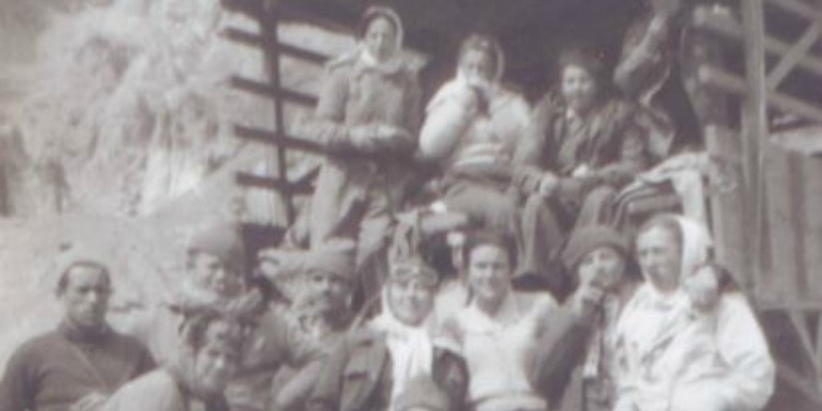 Group of people outside standing in and by a carriage.