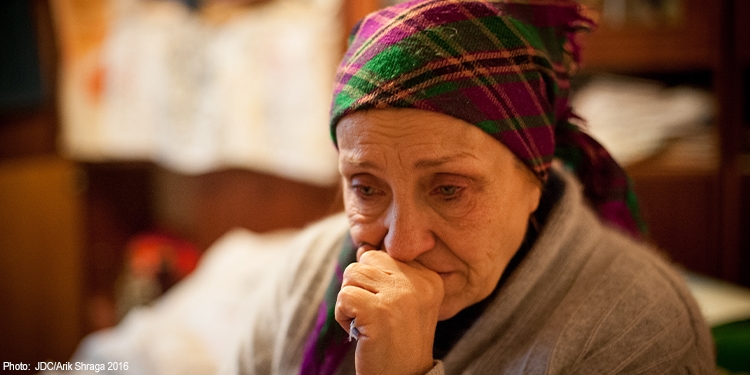 Woman in a plaid scarf looking down in sadness.