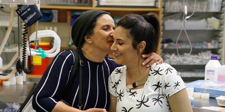 Women in a black shirt kissing her daughter on the cheek.