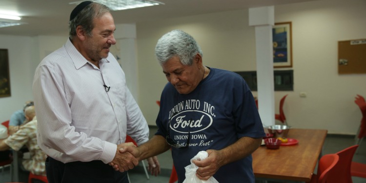 Rabbi Yechiel Eckstein shaking the hand of another man.