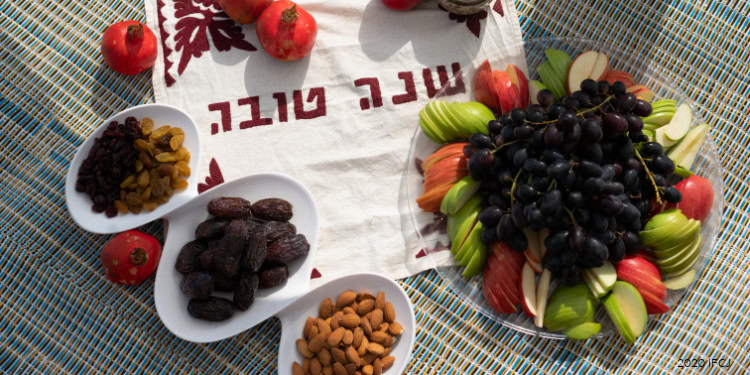 Colorful fruit and snack platter for Rosh Hashanah celebration, featuring grapes, apples, and dried fruits, symbolizing a sweet new year.