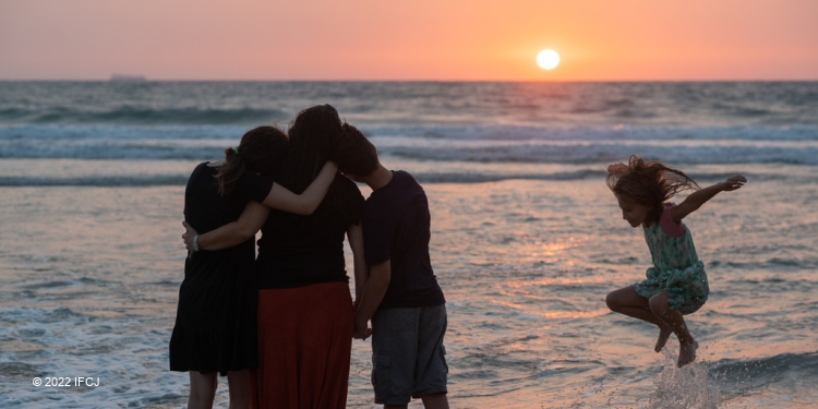 Yael Eckstein comforts her children at sunset on Israel shoreline