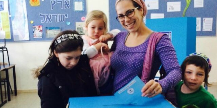 Yael Eckstein, surrounded by three children, place a ballot into a voting box.