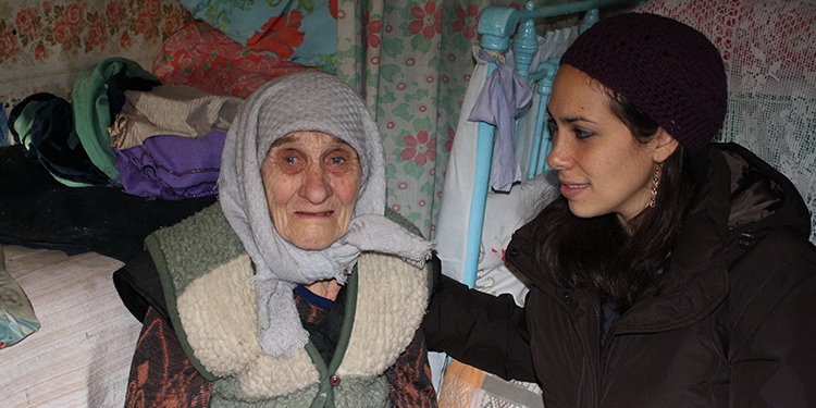 Yael Eckstein with elderly woman, light blue scarf wrapped around head