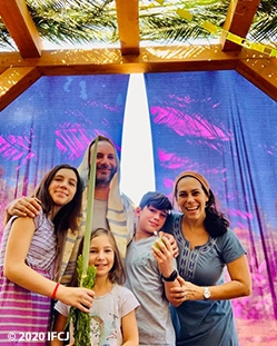 Yael Eckstein with her family standing in their sukkah.