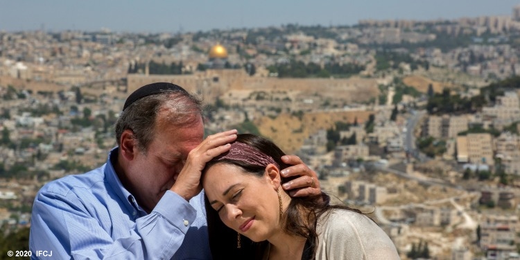 Rabbi Eckstein praying over his daughter while Jerusalem is in the background.