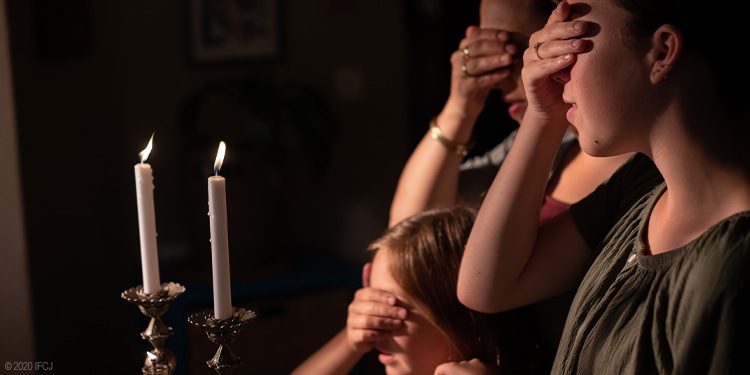 Yael and her daughters praying while their eyes are covered.