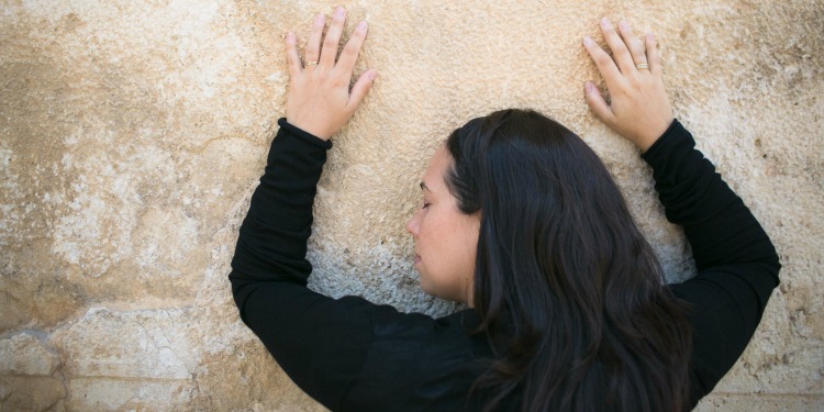Yael Eckstein with her hands over her head praying at the Western Wall.