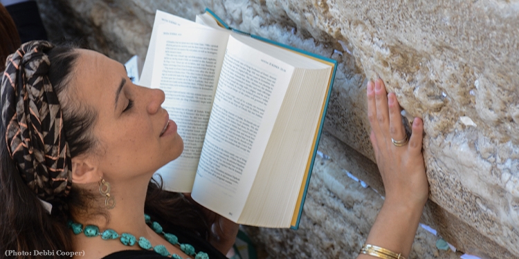 Yael praying at the Western Wall with a Bible in hand.