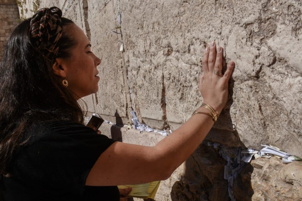 Yael Eckstein praying with her right hand touching the Western Wall.