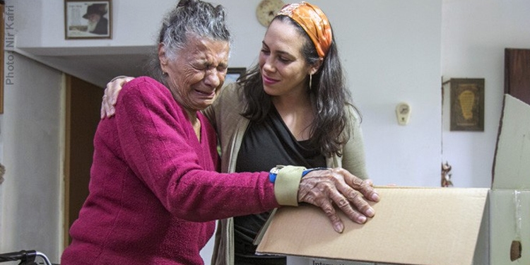 Yael Eckstein smiling and embracing a crying elderly Jewish woman.