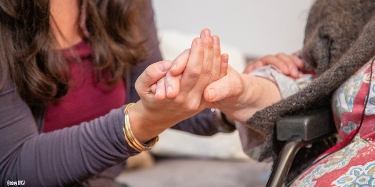 Close up image of Yael Eckstein holding hands with an elderly Jewish woman.