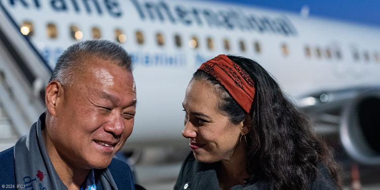 Yael speaking with man outside an airplane