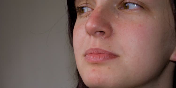 Close up image of a young woman in tears looking off into the distance.