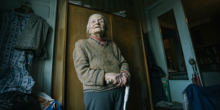 Yulia, an elderly Jewish woman standing in her room.