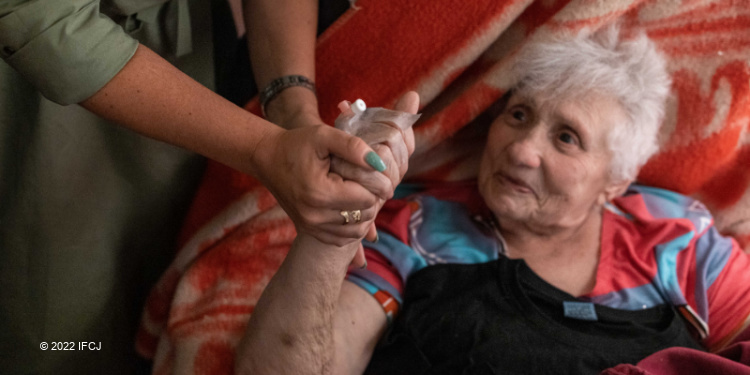 Elderly Jewish woman smiling at Yael Eckstein while they hold hands