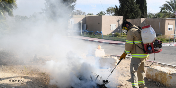 Man in a hazard suit putting out a fire.