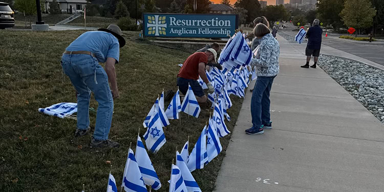 People placing Israeli flags at a memorial site during a community event, honoring heritage and unity.