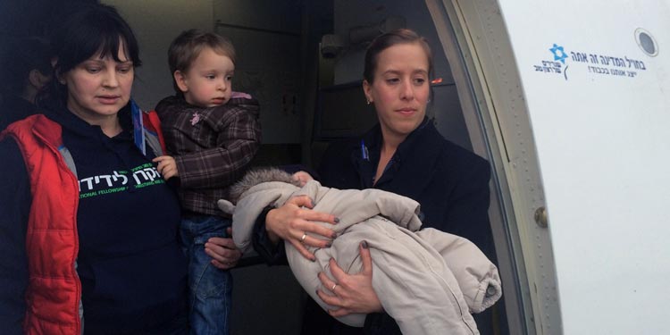 A mother and her two children coming off an Aliyah flight alongside an IFCJ volunteer. 