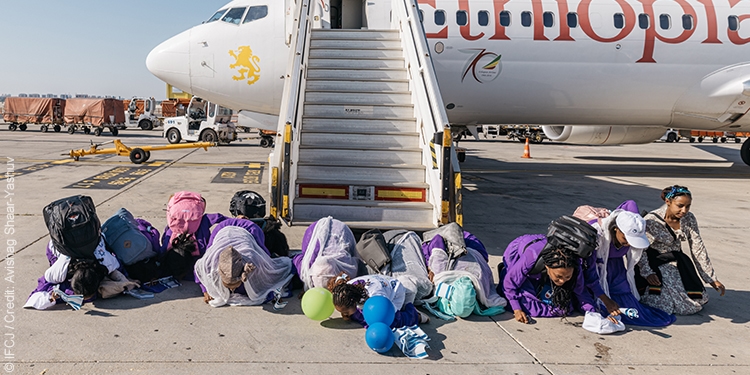 A group of Ethiopians kneeling and kissing the ground after stepping off of a plane to Israel.