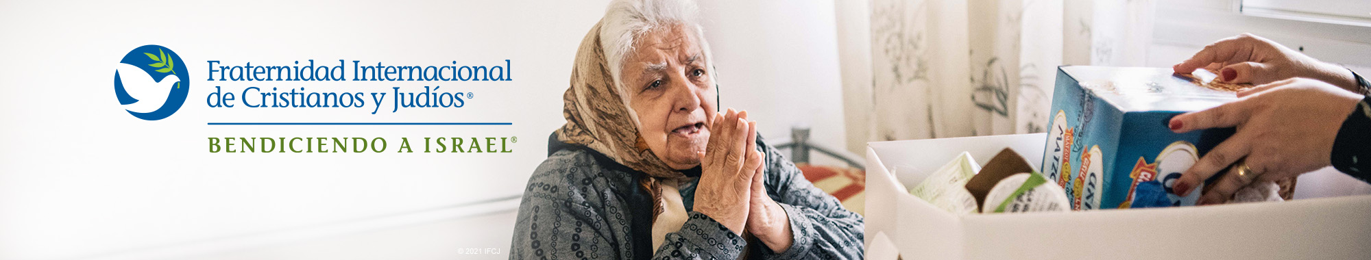 Elderly Jewish woman praying as an IFCJ food box is being handed to her.