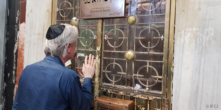 Bishop Paul Lanier with his hand up to a glass window at the Tomb of the Patriarchs.