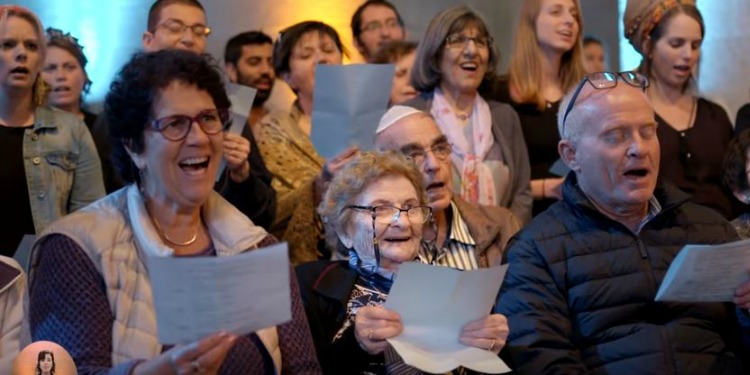 Several people holding on to a piece of paper while singing.