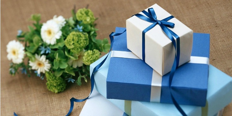 Four white and blue box gift boxes next to a green and white flower bouquet.