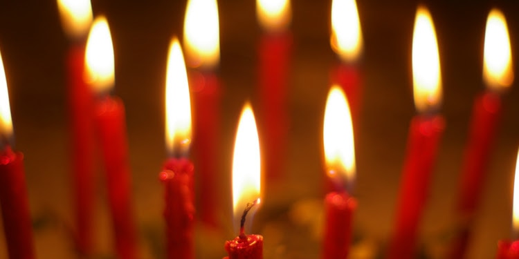 Close up image of several red candles lit.