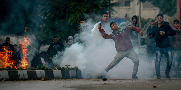 Boy holding smoke with several other men behind him.