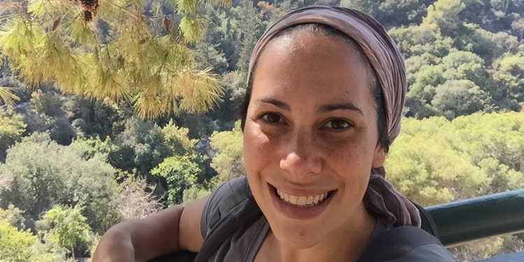 Yael Eckstein smiling into the camera with a forest behind her.