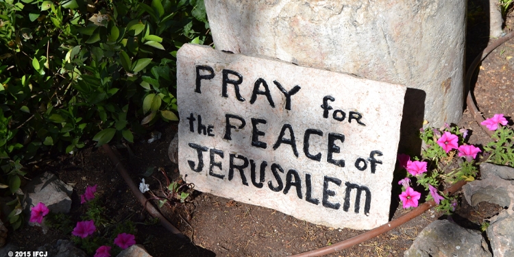 Granite sign on the floor next to flowers that reads 