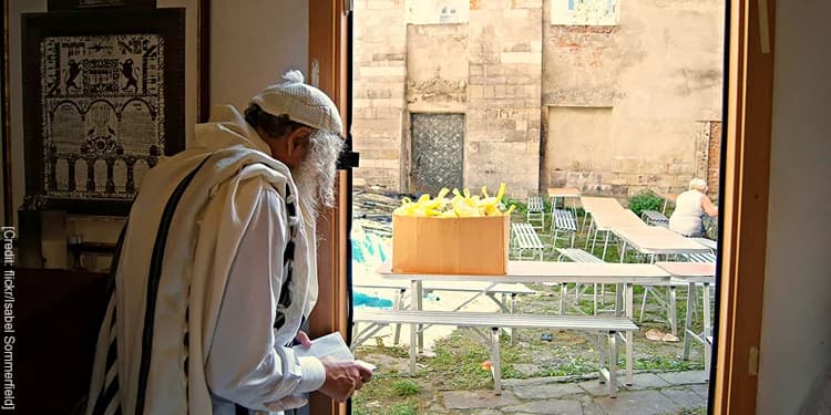 Elderly man flipping through a book while he's about to walk outside.