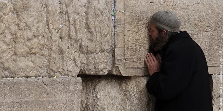 Man praying at a wall.