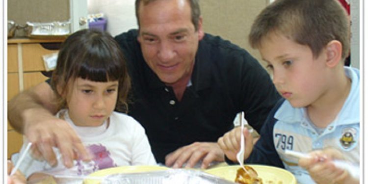 Rabbi Eckstein sitting with two children during snack time.