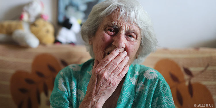 Elderly woman with hand on face covering her mouth