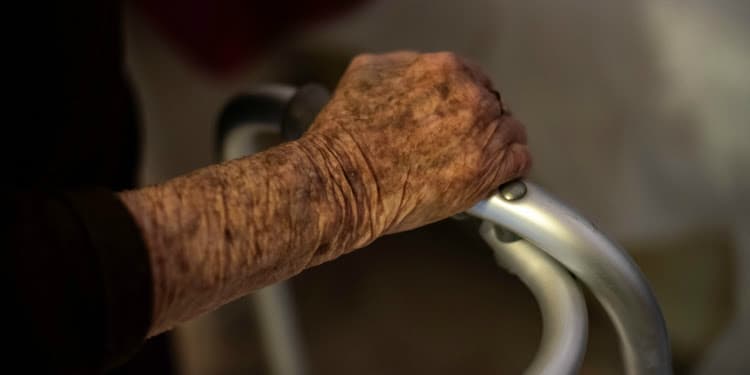 Close up image of elderly hands on a walker.