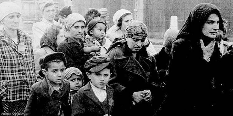 Jewish women and children from Subcarpathian Rus who have been selected for death at Auschwitz-Birkenau walk toward the gas chambers.
