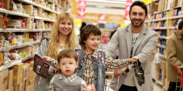 A young, smiling family shopping in a supermarket