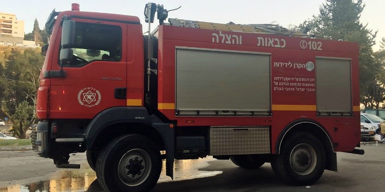 A parked fire truck with Jewish writing on the sides of it.