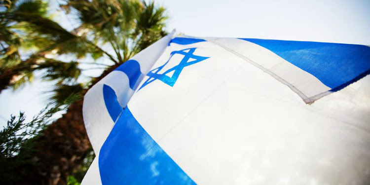 Close up image of an Israeli flag against palm trees.