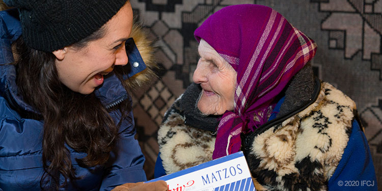 Yael Eckstein holds matzah box sits next to elderly woman