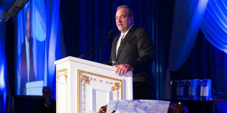Rabbi Eckstein giving a speech at a white podium.