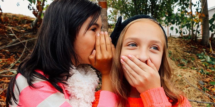 Two young girls whispering to each other.