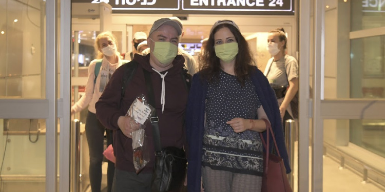 man and woman wearing masks outside of airport entrance after making aliyah