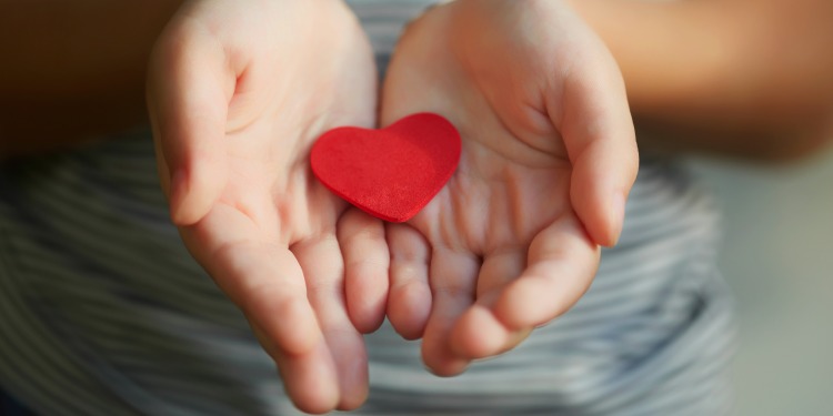 young girl holding red heart in open hands