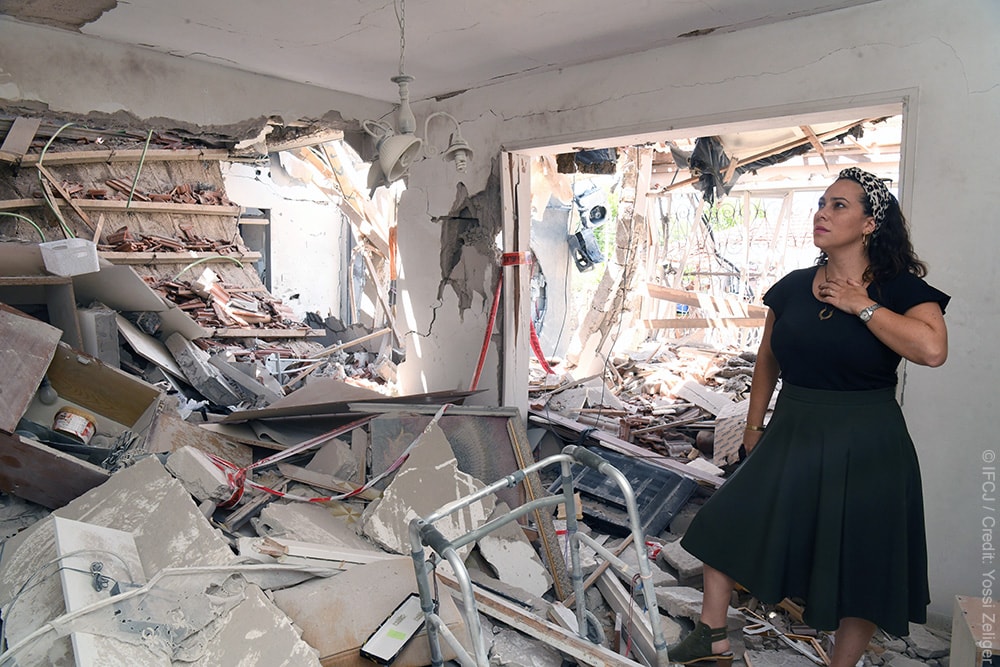 Yael standing in a home that was damaged by a rocket.